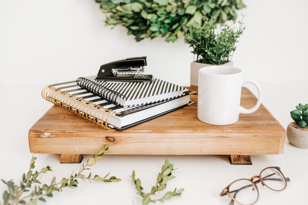 Greenery with office supplies, mug, glasses, stapler, notebook