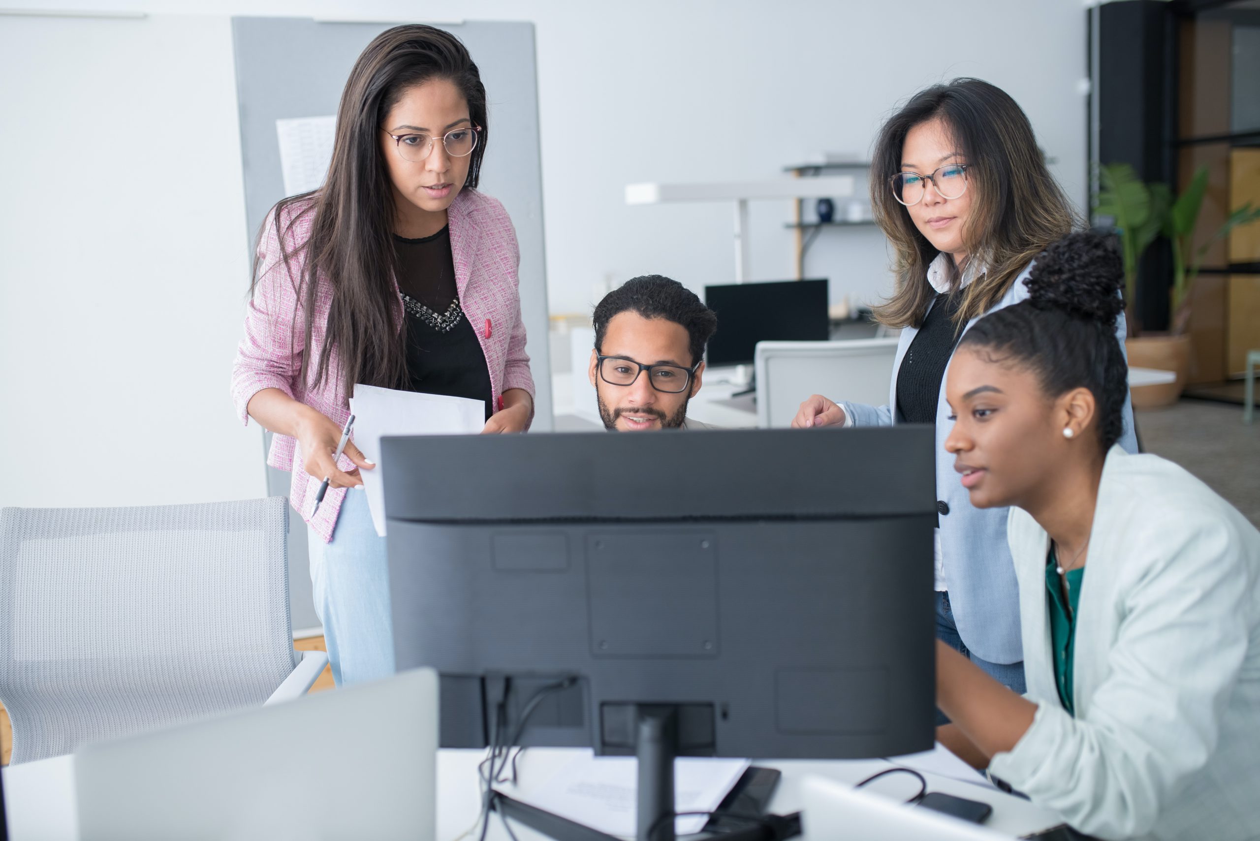 Diverse group of professionals huddled around a computer