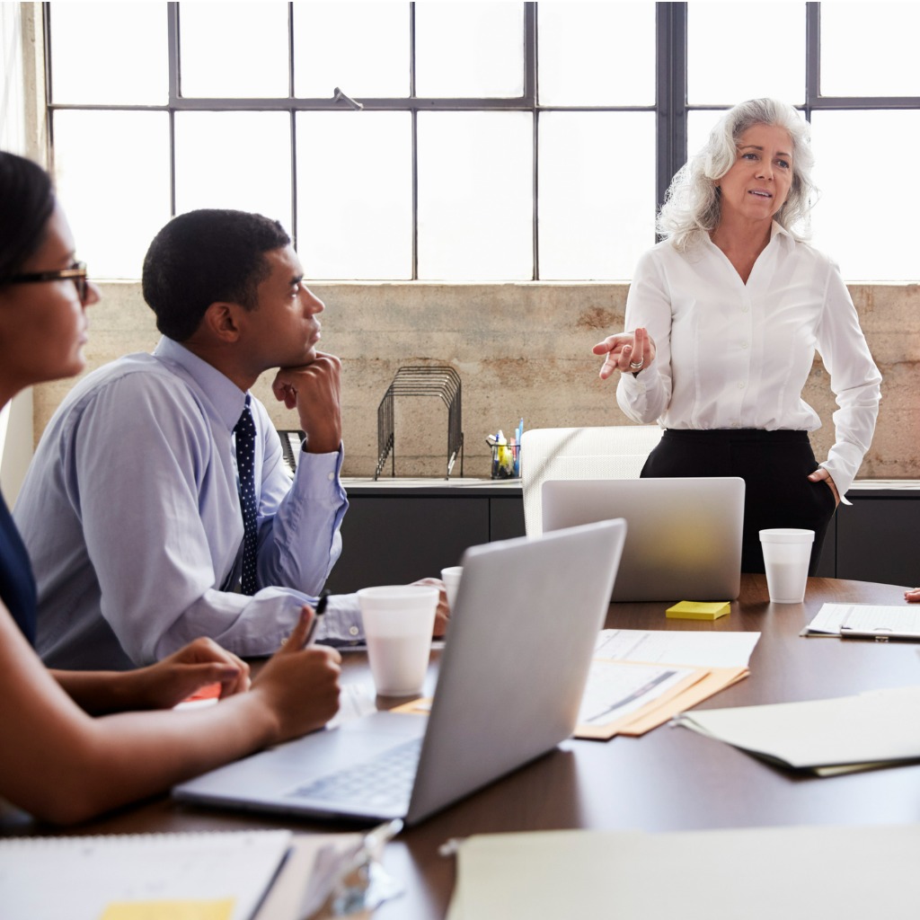 female-manager-stands-addressing-team-at-brainstorm-meeting.jpg_s=1024x1024&w=is&k=20&c=QJCf9PQ61j4tv-LflCvcU0zV1hjY-pNIruSVg-xZ_ZE=